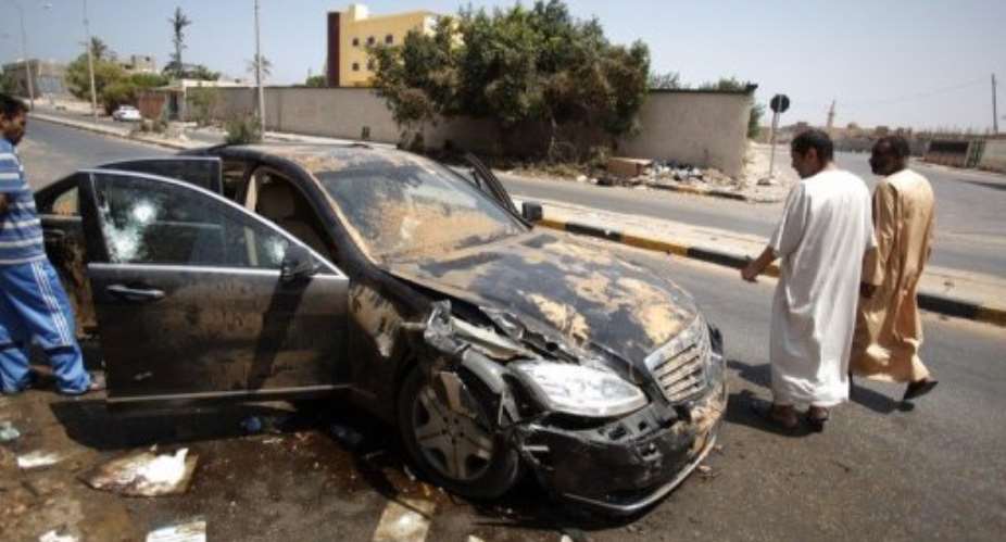 Libyans walks past the destroyed bullet proof car of Libyan former Prime Minister Baghdadi al-Mahmoudi in Tripoli.  By Patrick Baz AFPFile
