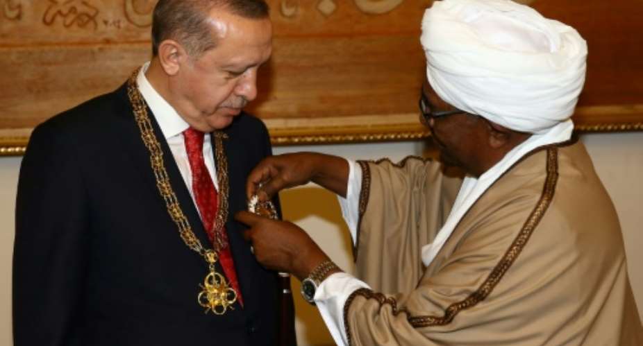 Turkey's President Recep Tayyip Erdogan L is decorated by his Sudanese counterpart Omar al-Bashir.  By KAYHAN OZER TURKISH PRESIDENTIAL PRESS SERVICEAFP
