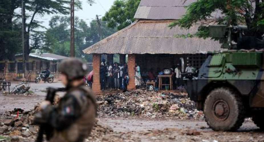 French soldiers of the Sangaris force patrol as locals take shelter from the rain on July 8, 2014 in Bangui.  By Stephane de Sakutin AFPFile