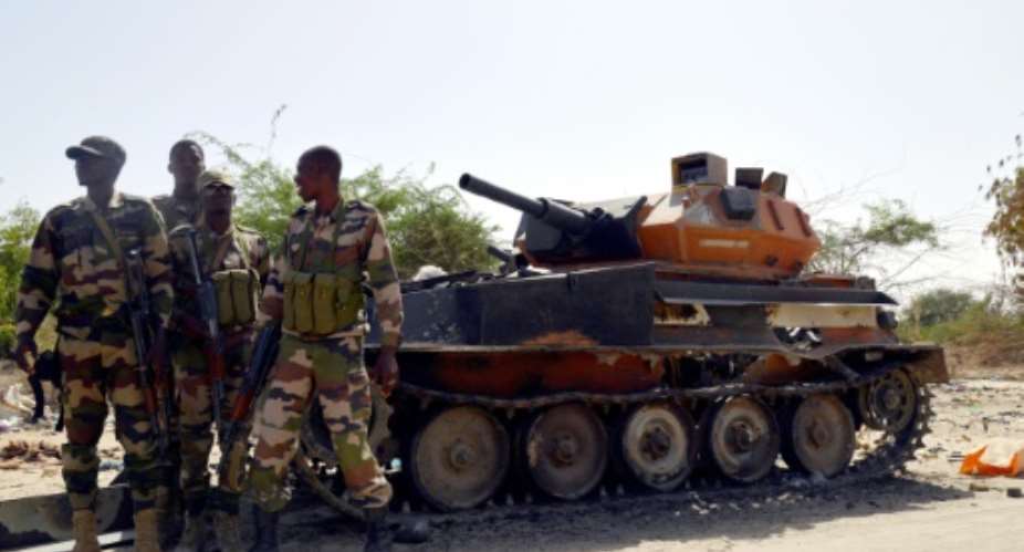 File picture shows Niger soldiers next to a burnt out tank belonging to the Boko Haram militants, in Malam Fatori, in northern Nigeria, near the border with Niger.  By Issouf Sanogo (AFP/File)