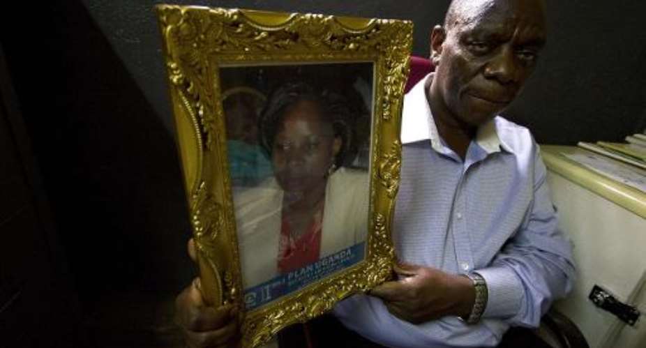Godfrey Wamala holds a picture of his late wife Remie, at his office in Kampala, on September 17, 2014.  By Isaac Kasamani AFPFile