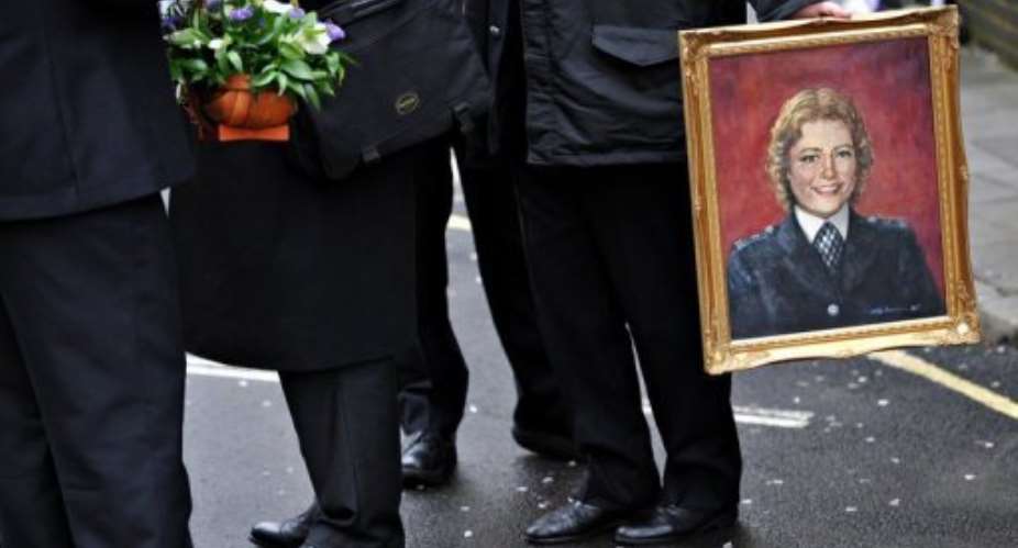 A police officer holds a portrait of the policewoman Yvonne Fletcher at a ceremony in London in 2009.  By Leon Neal AFPFile