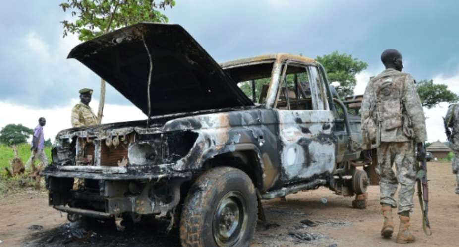 South Sudanese SPLA soldiers inspect a burned out car in Pageri on August 20, 2015.  By Samir Bol AFPFile