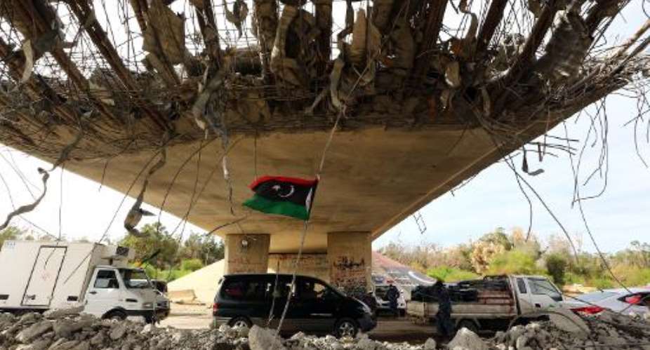 A Libyan flag flutters as cars wait under a bridge at a police checkpoint in Tripoli on September 9, 2014.  By Mahmud Turkia AFPFile