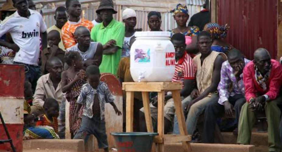 People sit on November 17, 2014 near a container to wash hands in the village of Kouremale, Mali, near the border with Guinea, to help stop the spread of Ebola.  By Habibou Kouyate AFPFile