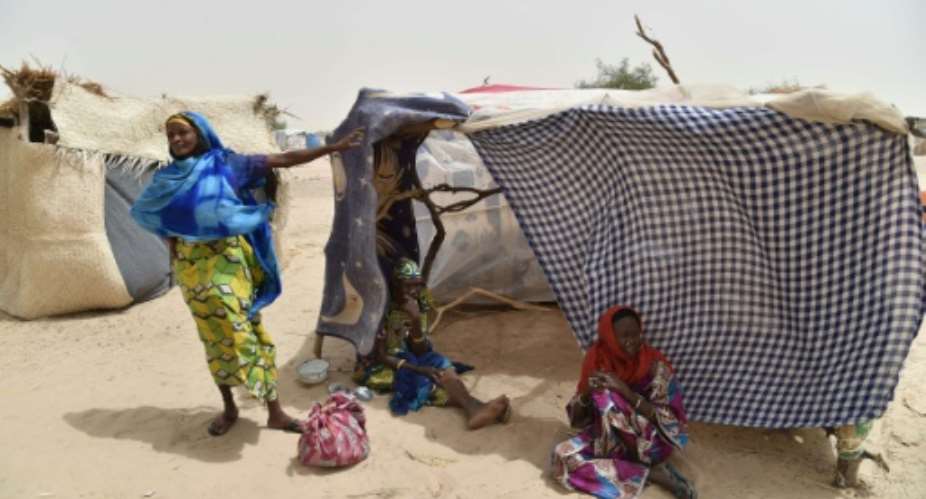 This photo taken on June 19, 2016 in the village of Kidjendi near Diffa shows women standing near makeshift tent in a camp as displaced families fled from Boko Haram attacks in Bosso.  By Issouf Sanogo AFPFile