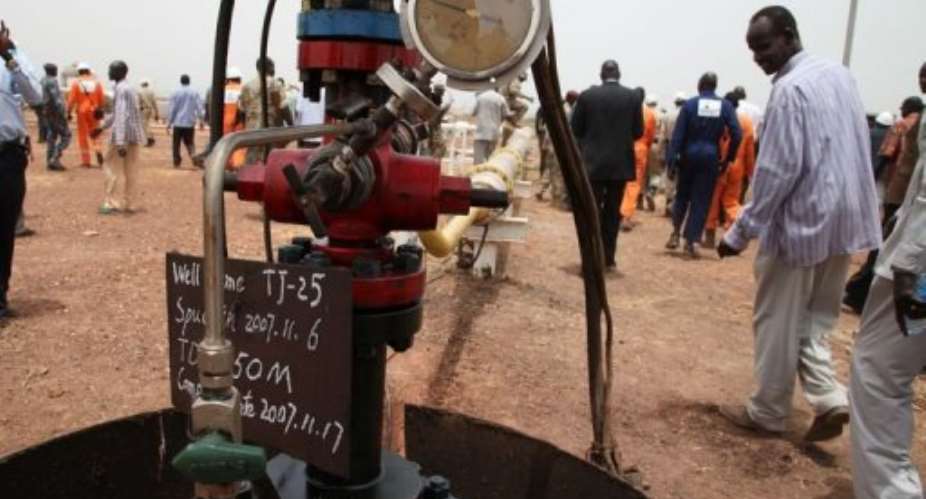 Oil mining employees walk near the first well to restart production in the Thar Jath field on April 6, 2013.  By Hannah McNeish (AFP/File)