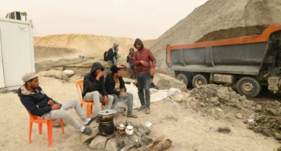 Unemployed Tunisians sit at a phosphate mine in the Metlaoui region on March 8, 2018, part of protests over government neglect that have disrupted production.  By FETHI BELAID AFP