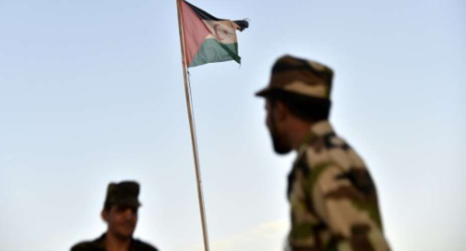 Uniformed soldiers of the pro-independence Polisario Front stand before a Sahrawi flag flying at the Boujdour refugee camp near the town of Tindouf in Western Algeria in October 2017.  By RYAD KRAMDI AFPFile