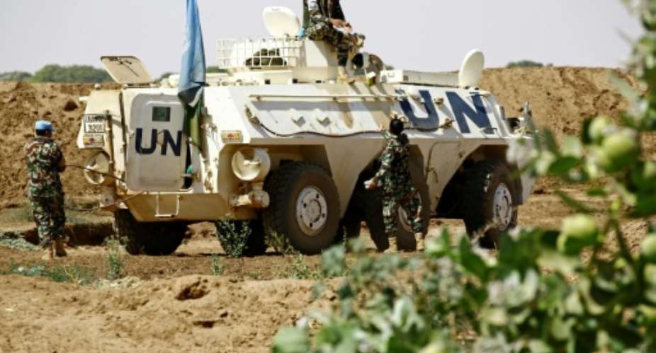 United Nation peacekeepers rest next to an armoured personnel carrier about 60 kilometres north of El-Fasher, the capital of the North Darfur state, on February 9, 2017.  By ASHRAF SHAZLY AFP