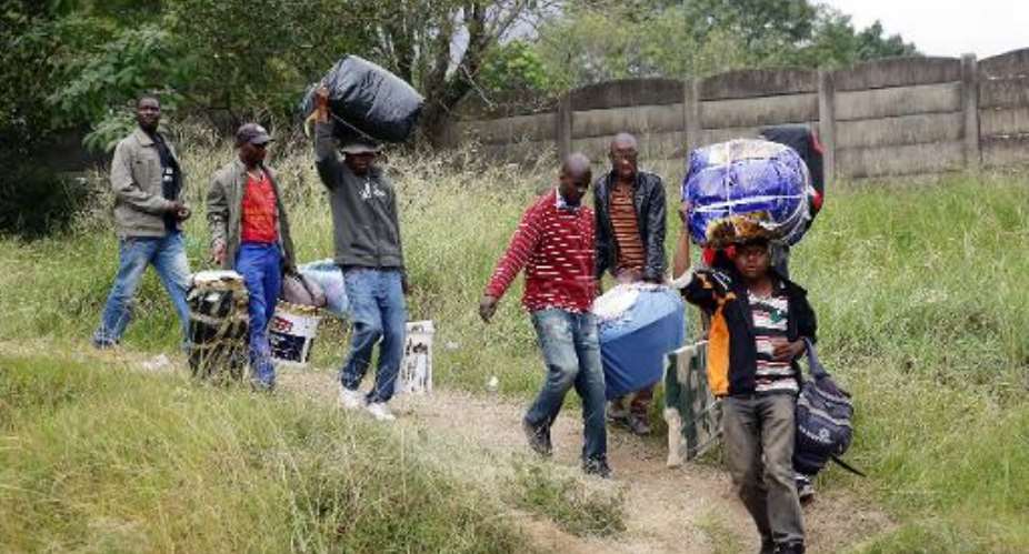 Foreign nationals carry their belongings before boarding a bus back to Zimbabwe in Chatsworth, South Africa on April 19, 2015.  By Rajesh Jantilal AFPFile