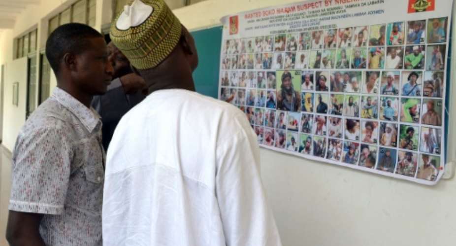 People look at a poster displaying Boko Haram suspects declared wanted by the Nigerian army in Maiduguri on October 28, 2015.  By  AFPFile
