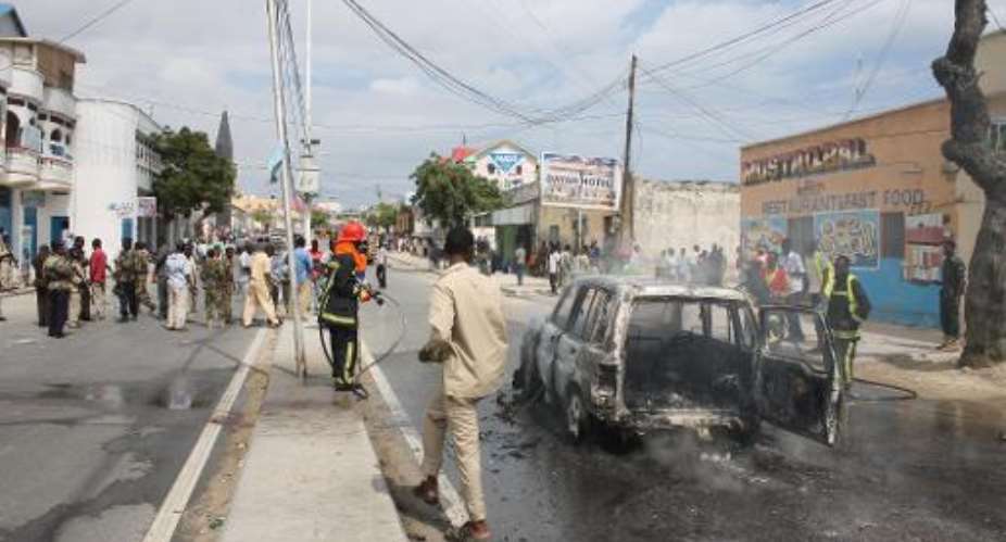 Firefighters extinguish the flames of a car hit by an explosion in Mogadishu, on November 16, 2014.  By Abdifitah Hashi Nor AFPFile
