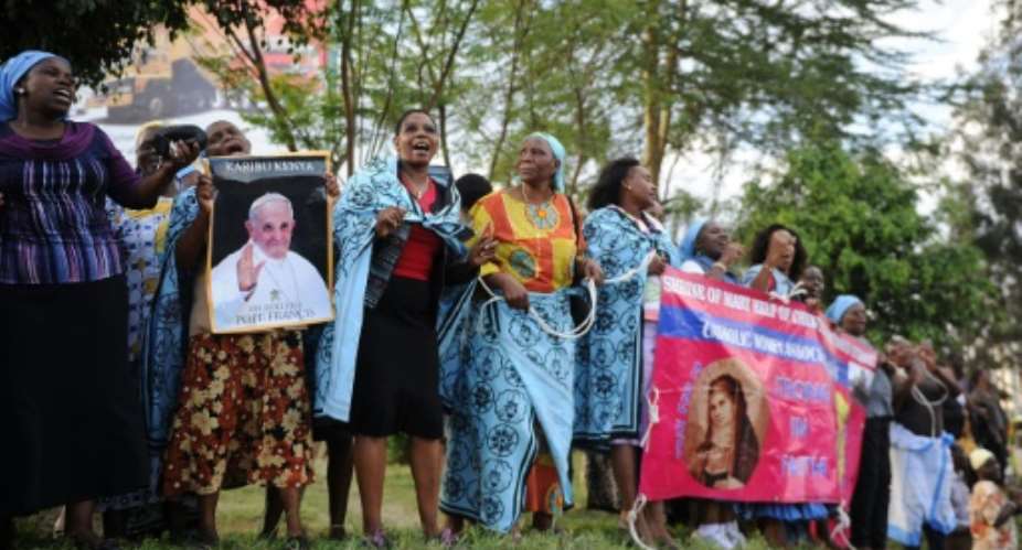 Catholics sing by the roadside carrying posters and welcome-banners for Pope Francis as they wait for his motorcade in the Kenyan capital, Nairobi November 25, 2015.  By Tony Karumba AFP