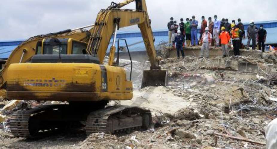 Rescue workers stand by as a caterpillar tries to excavate rubble of the collapsed building in search of missing persons at the Ikotun headquarters of the Synagogue Church of All Nations in Lagos on September 17, 2014.  By Pius Utomi Ekpei (AFP/File)