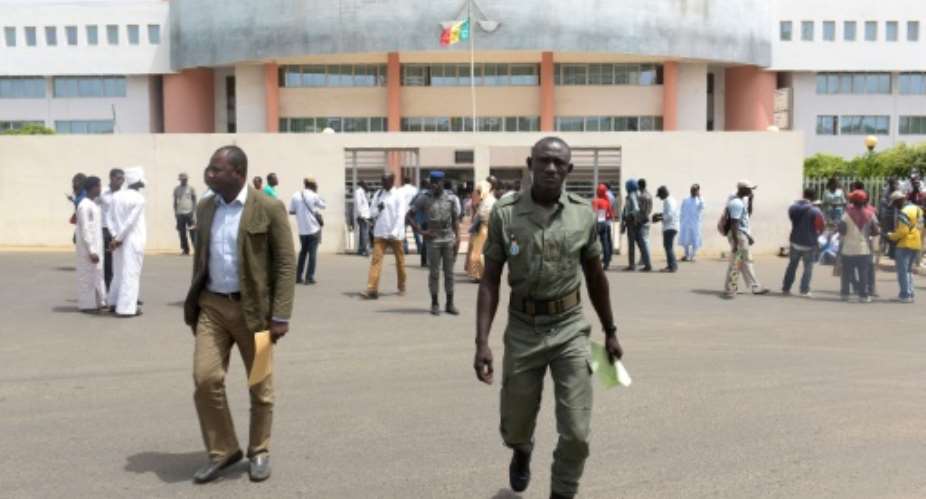 Senegalese security forces and civilians walk outside the Dakar courthouse on May 30, 2016.  By Seyllou AFP
