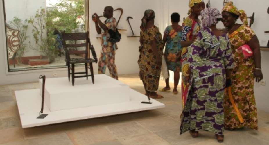 Visitors contemplate artefacts recently returned to Benin and on show at Cotonou's Petite Muse de la Recade.  By Prosper Dagnitche AFP