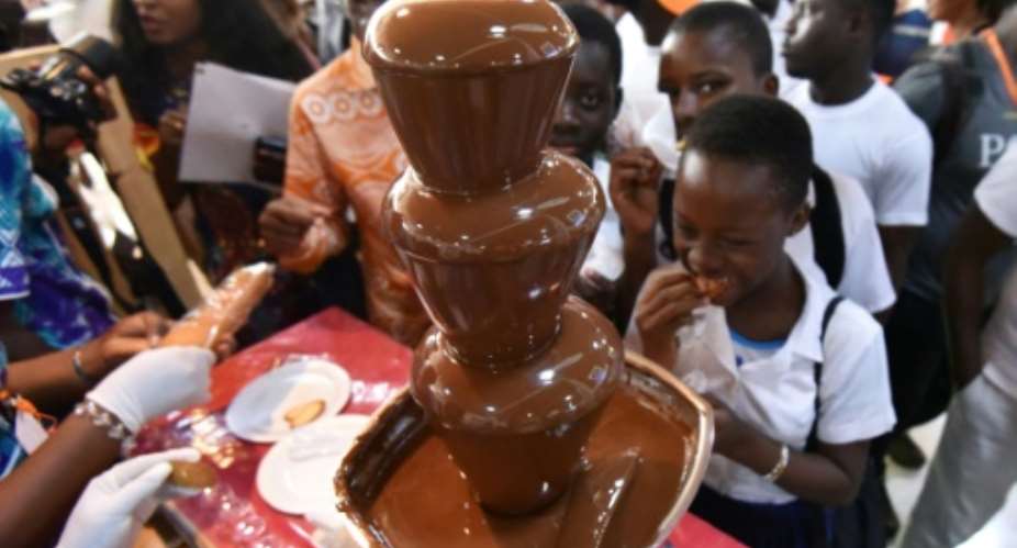 Visitors gather around a chocolate fountain at the opening of the fourth national cocoa and chocolate days in Abidjan.  By Sia KAMBOU AFP