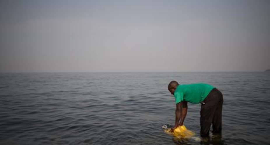 A man fills a jerrycan with water from Lake Kivu on the Himbi beach in Goma, in the east of the Democratic Republic of Congo on August 11, 2013.  By Phil Moore AFPFile