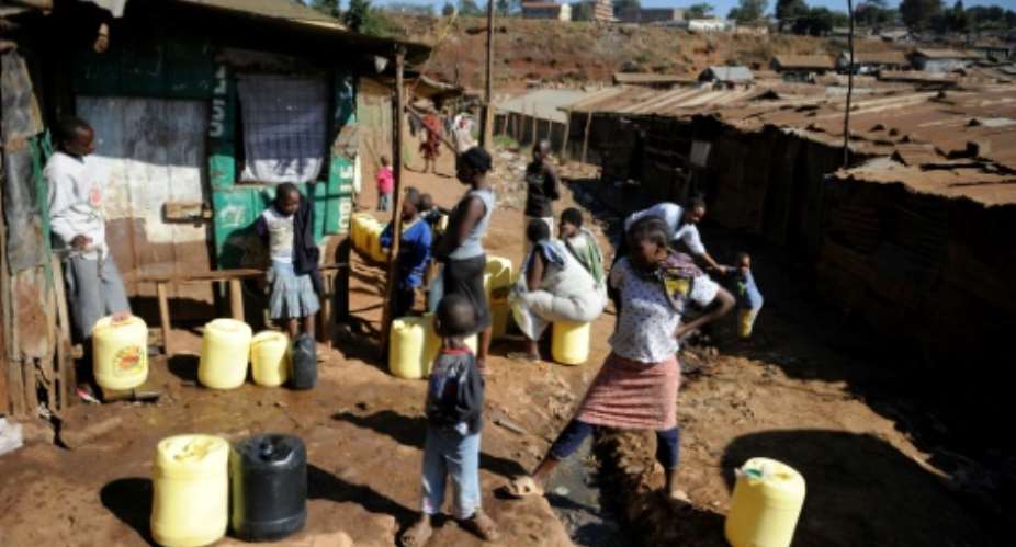 Local residents wait to fill their jerry cans with water at a distribution site in the Kibera slum of Nairobi.  By Tony Karumba AFP