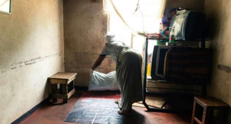 Where a child is born: Esther Gwena, 69, who acts as a midwife but has no training, lays down sheets in her rundown apartment -- a makeshift maternity unit.  By Jekesai NJIKIZANA AFP