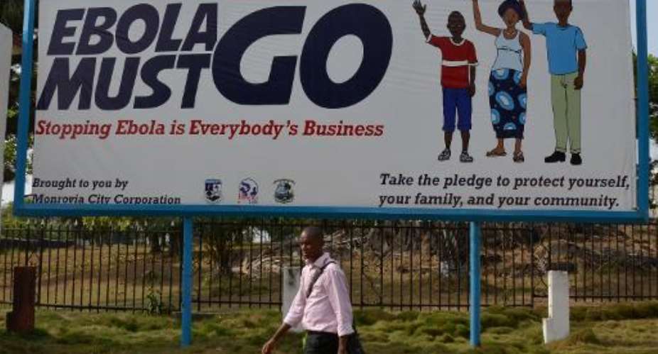 A man walks past an Ebola campaign banner with the new slogan Ebola Must GO in Monrovia, Liberia on February 23, 2015.  By Zoom Dosso AFPFile