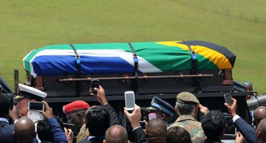 People take pictures as the coffin of South African former president Nelson Mandela is carried on a gun carrier for a traditional burial during his funeral in Qunu on December 15, 2013.  By Felix Dlangamandla PoolAFP