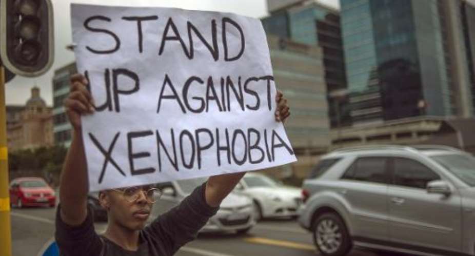 A woman holds up a placard at a protest in Sandton, Johannesburg, on April 18, 2015 against xenophobia.  By Mujahid Safodien AFP