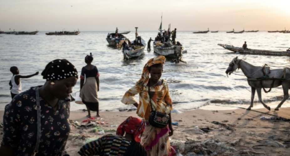 Women wait to buy fish off incoming boats at the port of Mbour. Poverty and dwindling catches have led many young people in Senegal's fishing communities to attempt the dangerous crossing to the Canary Islands.  By JOHN WESSELS AFP