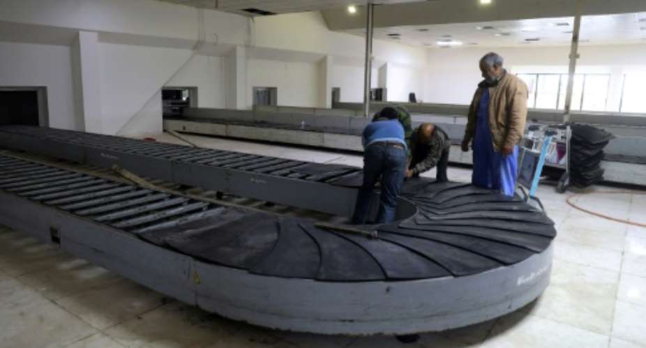 Workers at the Libyan capital's Mitiga airport.  By - AFP