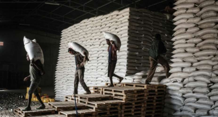 Workers carry sacks of wheat for food distribution in Mekele, the Tigrayan capital, in June 2021.  By Yasuyoshi CHIBA AFPFile