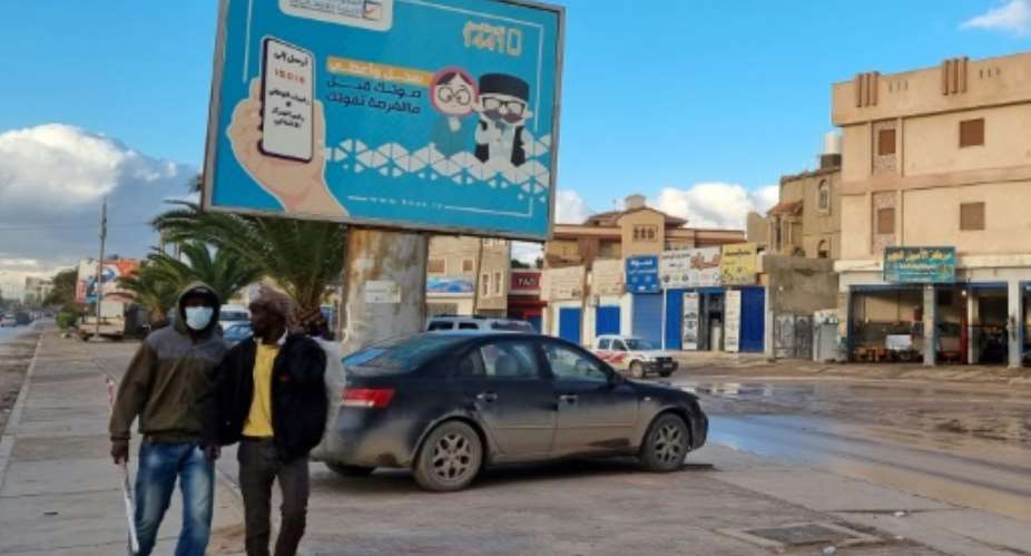 Workers in Libya's capital Tripoli pass an electoral billboard reading in Arabic, 'Register and vote before missing your chance' -- but a postponement of the ballot is widely expected.  By Mahmud TURKIA AFPFile