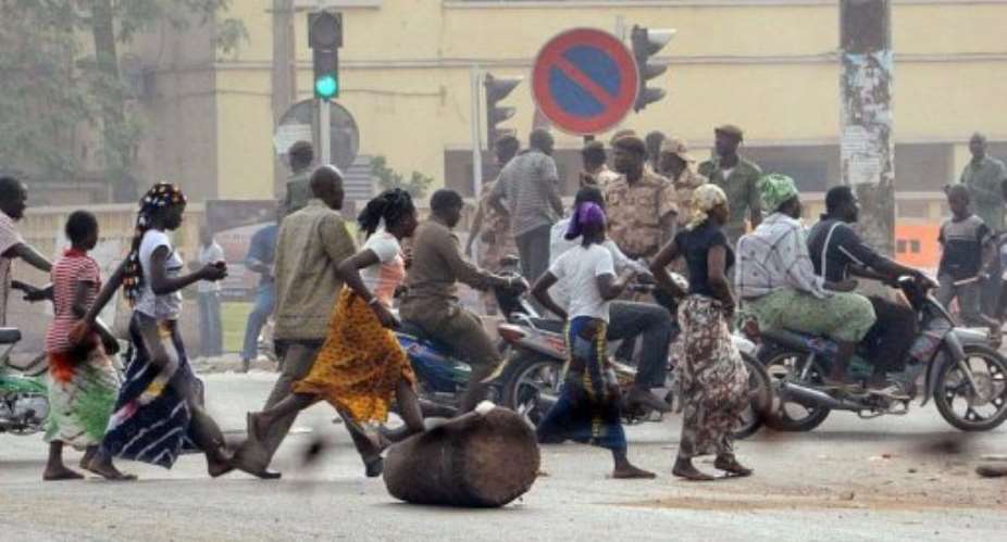 Residents run past soldiers in a street of Bamako.  By Habibou Kouyate AFP