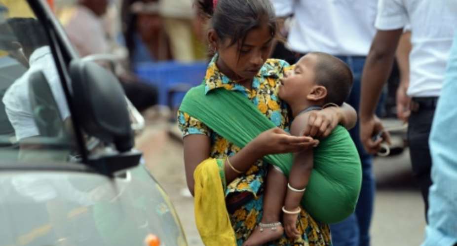 A girl carrying a toddler counts money collected by begging from commuters at a busy traffic intersection in Mumbai.  By Indranil Mukherjee AFPFile
