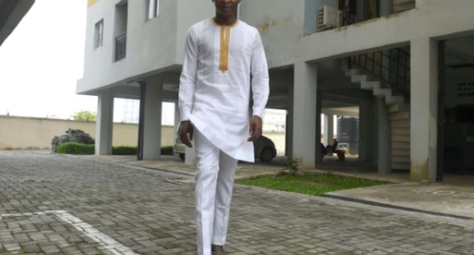 Young Nigerian men are turning from desiger jeans to traditional dress, like this white bua and sokoto style, starting a new fashtion trend.  By PIUS UTOMI EKPEI AFP