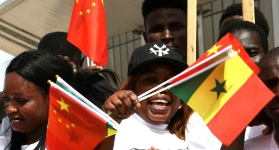 Young Senegalese wave flags to mark the arrival of President Xi on a state visit with China the west African nation's second biggest trading partner behind France, its firms having embarked on a slew of major infrastructure projects.  By SEYLLOU AFP