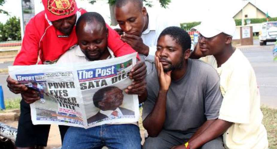 Taxi drivers read the news of President Michael Sata's death in The Post special edition on October 29, 2014 in Lusaka.  By Chibala Zulu AFP