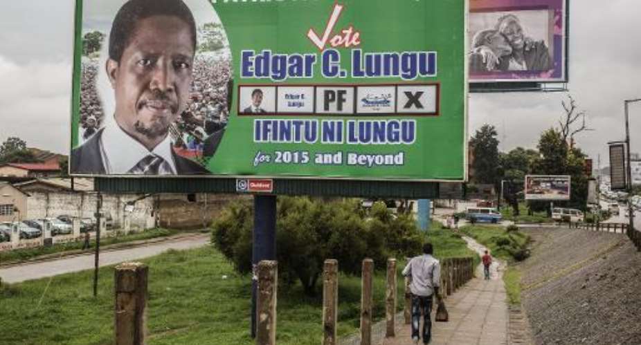 A man runs on January 19, 2015 past a giant billboard for the presidential candidate of the Zambian ruling party Patriotic Front, Edgar Lungu, on the eve of the Zambian presidential elections in Lusaka.  By Gianluigi Guercia AFPFile