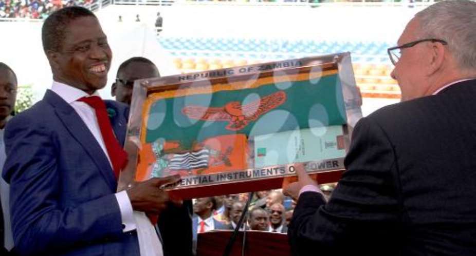 Zambia's newly elected President Edgar Lungu L receives the instruments of power from acting president Guy Scott R after being sworn in as Zambia's president, at the Heroes National Stadium in Lusaka on January 25, 2015.  By Salim Dawood AFP