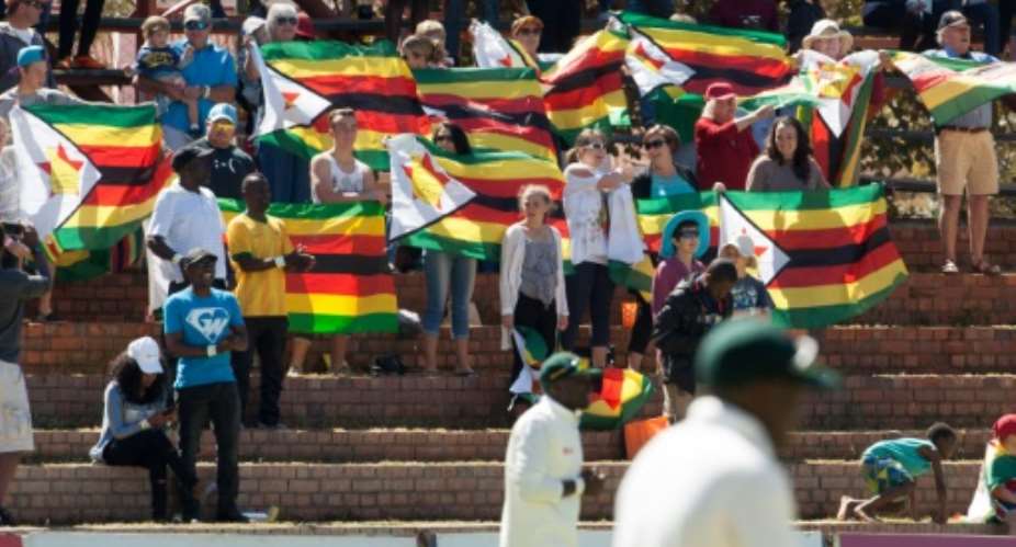 Zimbabwe cricket supporters sing the national anthem on the first day of the second Test against New Zealand at the Queens Sports Club in Bulawayo, on August 6, 2016.  By Jekesai Njikizana AFP