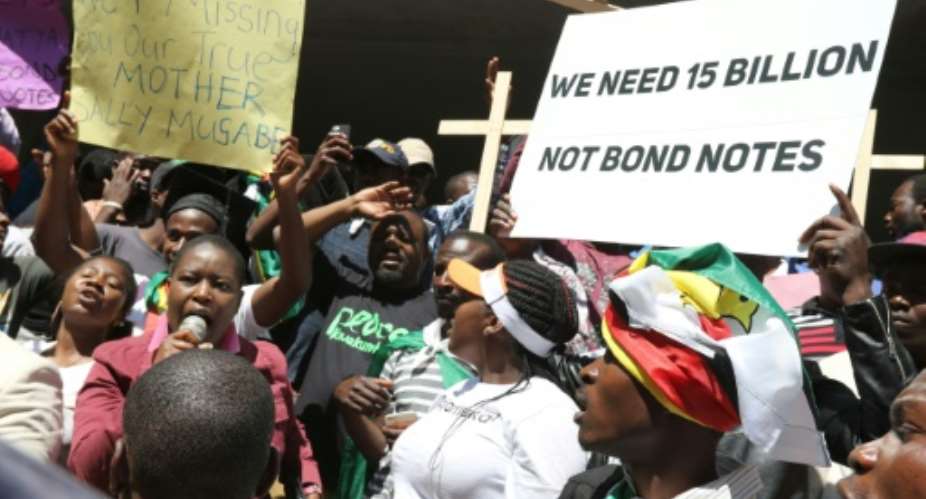 People hold crosses and banners during a protest against the introduction of new bond notes and youth unemployement on August, 3, 2016 in Harare, Zimbabwe.  By Wildref Kajese AFPFile