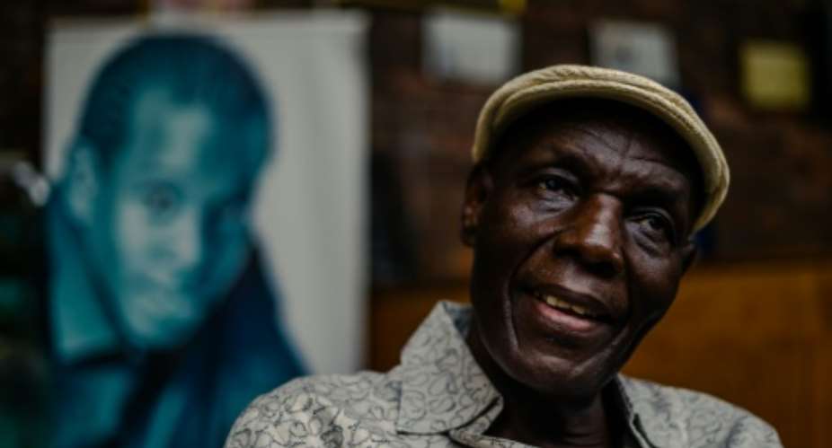 Zimbabwe music icon Oliver 'Tuku' Mtukudzi, pictured in January 2018. Over his shoulder is a portrait of his late son, Sam Mtukudzi.  By Jekesai NJIKIZANA AFP
