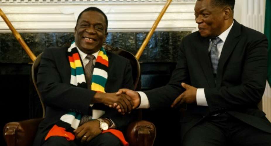 Zimbabwe President Emmerson Mnangagwa, seen here shaking hands with the newly-appointed prosecutor general Kumbirai Hodzi, has pledged to investigate any misconduct by the security forces.  By Jekesai NJIKIZANA AFP