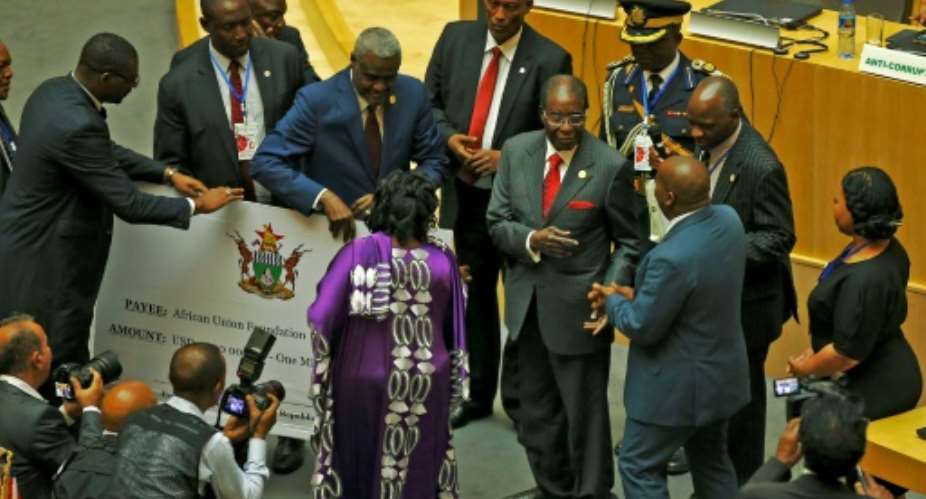 Zimbabwe's President Robert Mugabe, center, gives a 1 million cheque to the African Union  during a summit meeting in Addis Ababa, Ethiopia.  By SOLAN KOLLI AFP