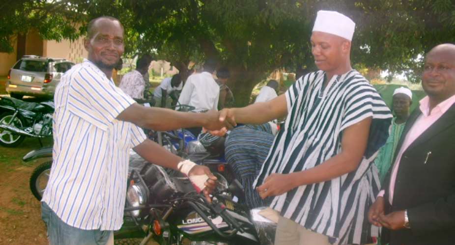 HON. ADAMS MUTAWAKILUDCE ON THE RIGHT PRESENTING THE KEYS TO ONE OF ASSEMBLYMEN.
