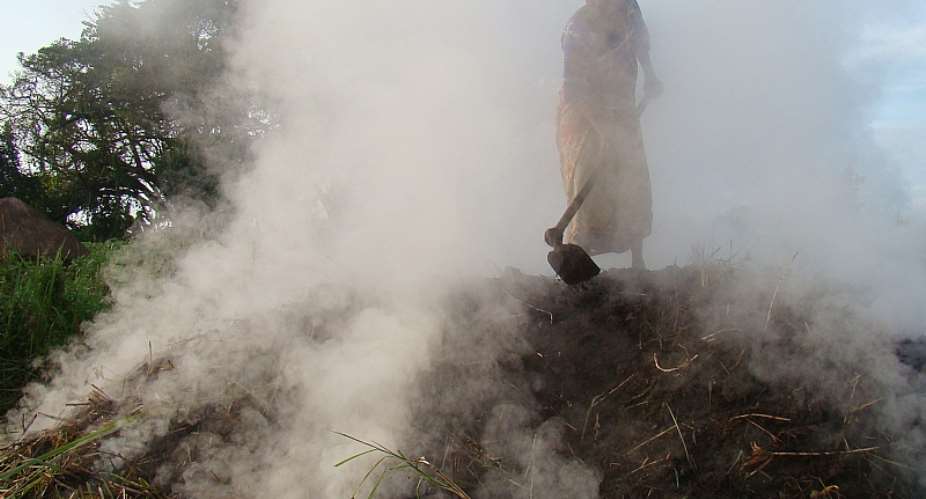 A woman standing on a heap of fuming charcoal furnace