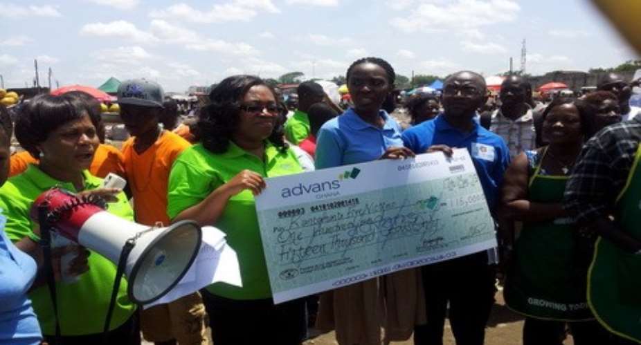 Barbara Odei (2nd L) and Solomon Larbey (R) presenting the cheque to the victims at Kantamanto market on Friday, May 17 2013.