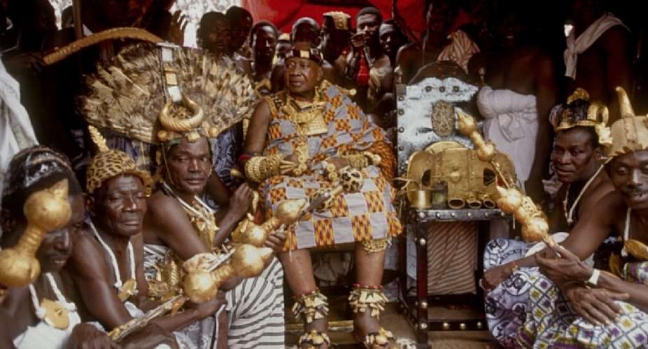 The late Asante King of Ghana; Otumfuo Opoku Ware II seated fourth from left in photo with his subjects and adorned in Ashanti Kente cloth and gold, to his right is the legendary Golden stool.