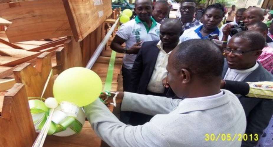 The Board Chairman of the school cuts the tape to receive the items from ASECOSA, whilst the Vice President, the Headmaster and other members look on admiringly.