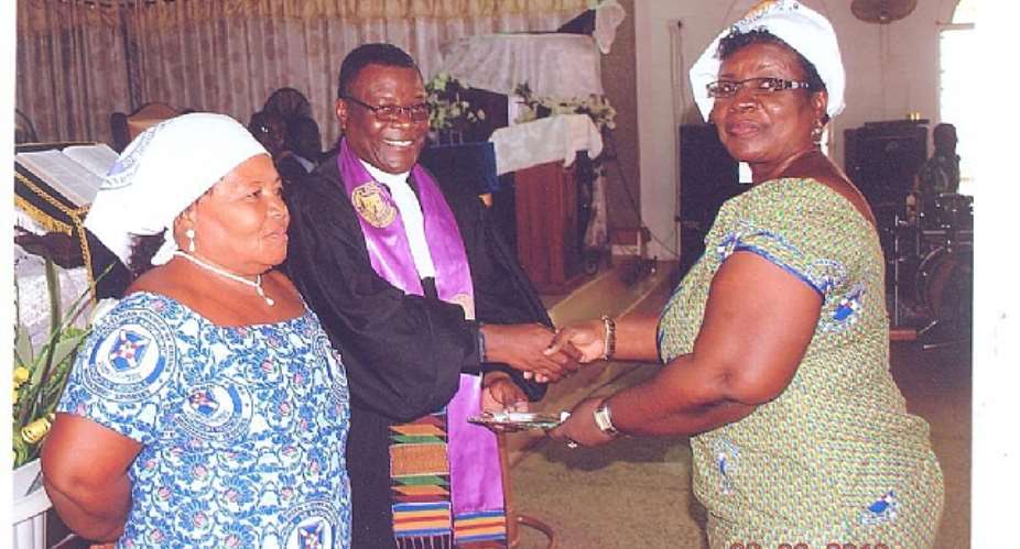 Rev. Enoch Adjei Pobee standing inducting Rev. Mark Boye. Left is his wife, Regina